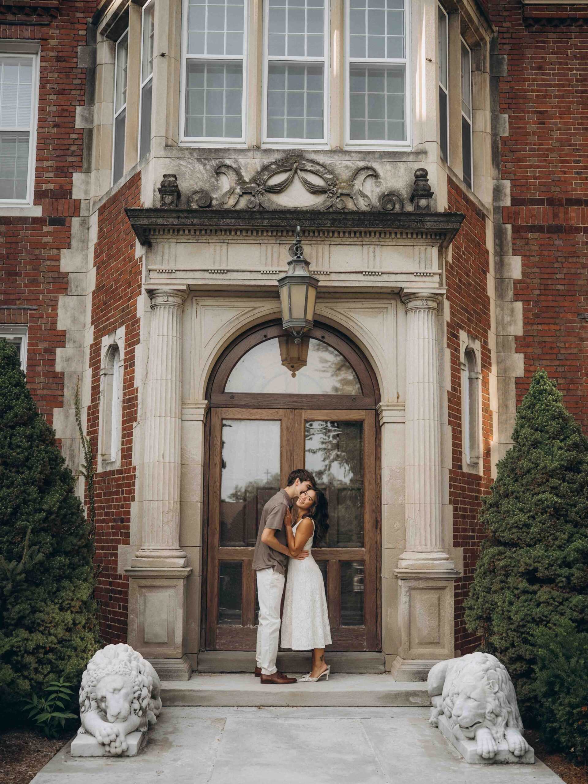 grand rapids engagement photographer captures picture of couple smiling in front of Aquinas building